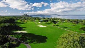 A golf course with a clear view of the ocean and a distant mountain.