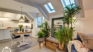 Un loft espacioso con cocina, comedor y sala de estar. Cuenta con tragaluces, plantas en macetas y una zona de estar acogedora.
