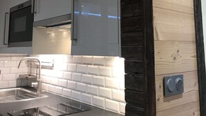 A modern kitchen with a black countertop, white subway tiles backsplash, and wooden paneling. - Modern, luxury studio in Morzine,1st floor, sleeps 4, centrally located (Morzine)
