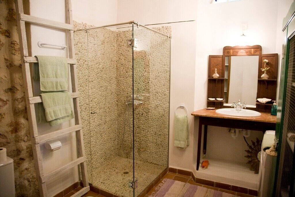 A bathroom with a glass shower enclosure, a wooden vanity with a mirror, and a towel rack.