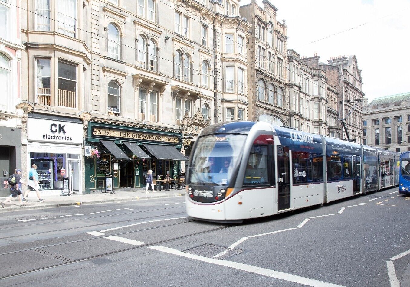 A tram on a city street with buildings in the background.