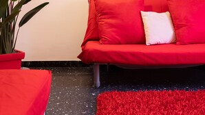 A modern living room with a red sofa, a red rug, a potted plant, and a painting of a tree-lined pathway. - La Casa di Azzurra for Cinque Terre<br>Cod.Citra 011015-LT-0171 (La Spezia)