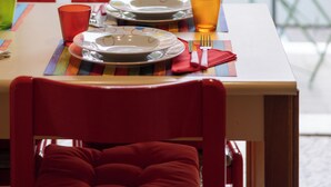 A dining table set with plates, glasses, and cutlery, with a view of a green garden and a red car through a glass door. - La Casa di Azzurra for Cinque Terre<br>Cod.Citra 011015-LT-0171 (La Spezia)