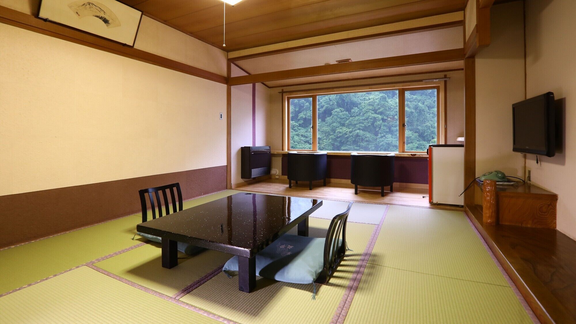 Una habitació amb esteres de tatami, una taula baixa, cadires, un altaveu i una televisió.
