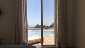Un dormitori amb un gran finestral corredís que dona a una zona de piscina.