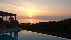 A swimming pool with a sunset view, lounge chairs, and a covered patio area. - house / villa - Solenzara (Sari-Solenzara)