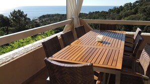 A wooden table with wicker chairs on a balcony overlooking the sea. - house / villa - Solenzara (Sari-Solenzara)