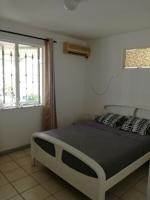 Cozy retreat with a single bed, air conditioning, and a window with a metal grill.