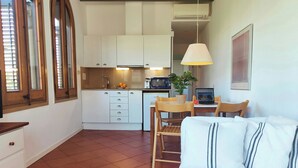 A compact living space with a kitchenette, a dining area with a table and chairs, and a sofa.