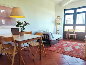 Una stanza con un tavolo da pranzo, sedie, un letto, una lampada e una finestra.