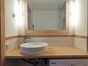 Une salle de bain avec un lavabo blanc, un meuble-lavabo en bois et un miroir.