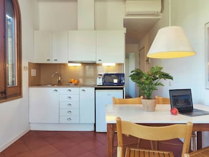 Una cucina compatta con mobili bianchi, un forno a microonde, un tostapane e un tavolo da pranzo con sedie.