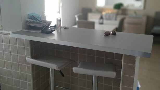 A kitchen with a white countertop, two bar stools, and a tiled backsplash.