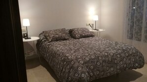 A bedroom with a bed, two bedside tables, and two lamps.