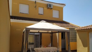 A yellow building with a covered patio area featuring a table and chairs.