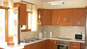 Une cuisine avec des meubles de rangement en bois, un évier, une cuisinière et un four à micro-ondes.