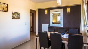 Un coin repas avec une table et des chaises, un miroir au mur et une vue sur une autre pièce.