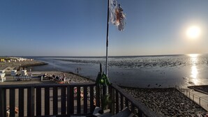 A beachside view with a sunlit sea, a wooden deck, and beach chairs. - Apart Seegras Exclusive vacation apartment in a prime location! (Büsum)