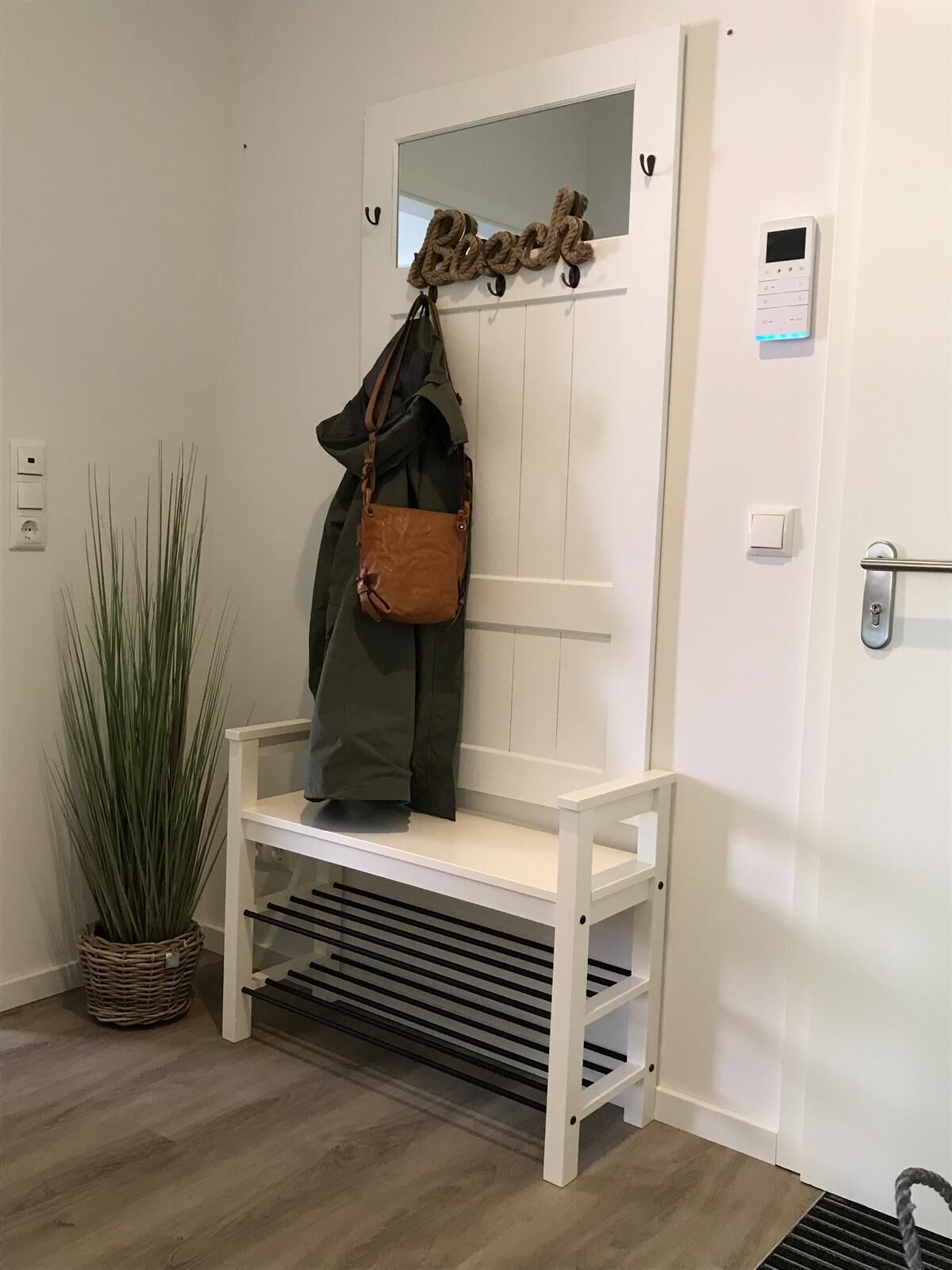 Un banc blanc avec un porte-manteau et un sac brun qui y est accroché.