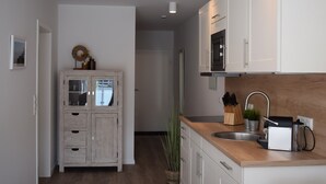 A modern kitchen with white cabinets, a wooden countertop, and a built-in microwave. - Apart Seegras Exclusive vacation apartment in a prime location! (Büsum)