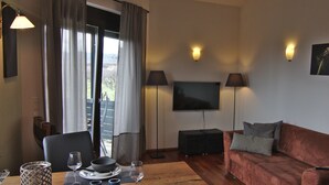 Ein Wohnzimmer mit einer Couch, einem Fernseher und einem Essbereich mit Tisch und Stühlen.