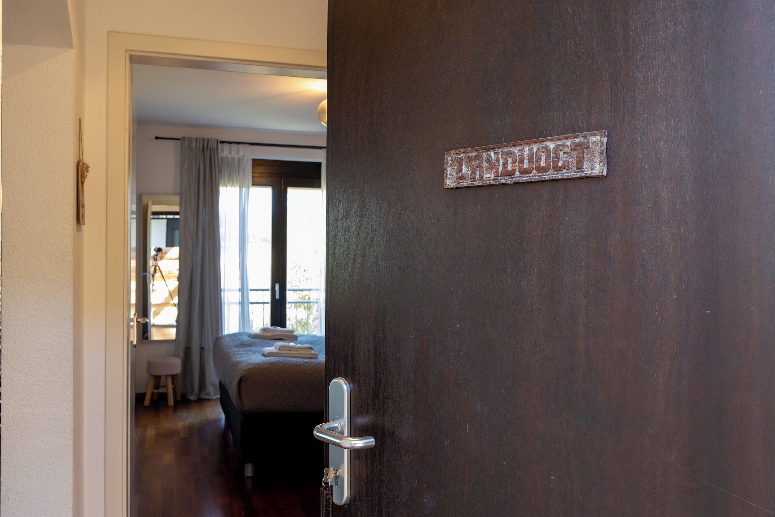 Une chambre d’hôtel avec un lit, une fenêtre avec des rideaux et une porte avec une pancarte.
