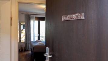 Une chambre d’hôtel avec un lit, une fenêtre avec des rideaux et une porte avec une pancarte.