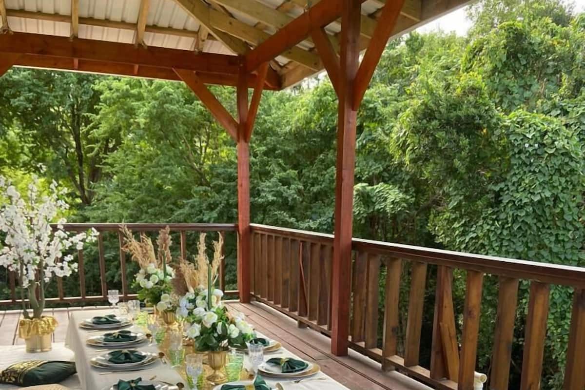 An outdoor dining area with a covered wooden deck, white tablecloths, and green napkins.
