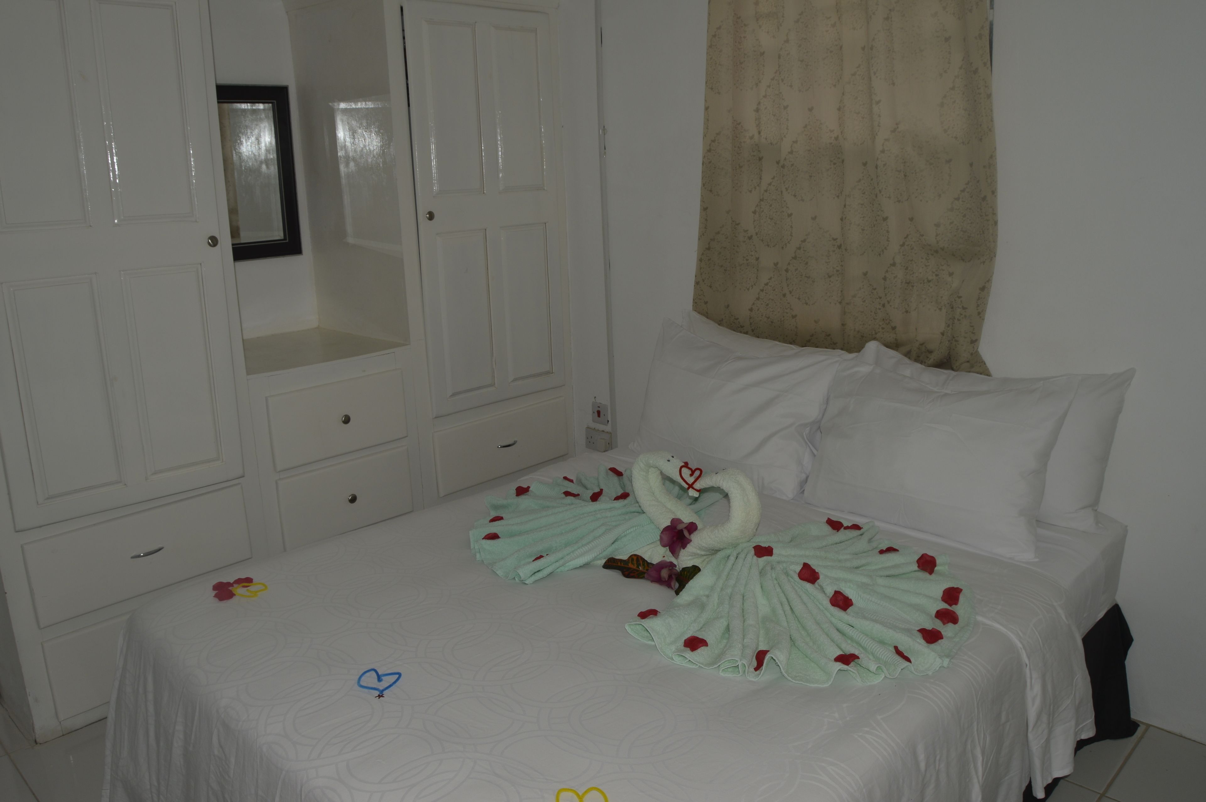 A hotel room with a neatly made bed, a wardrobe, and a mirror.