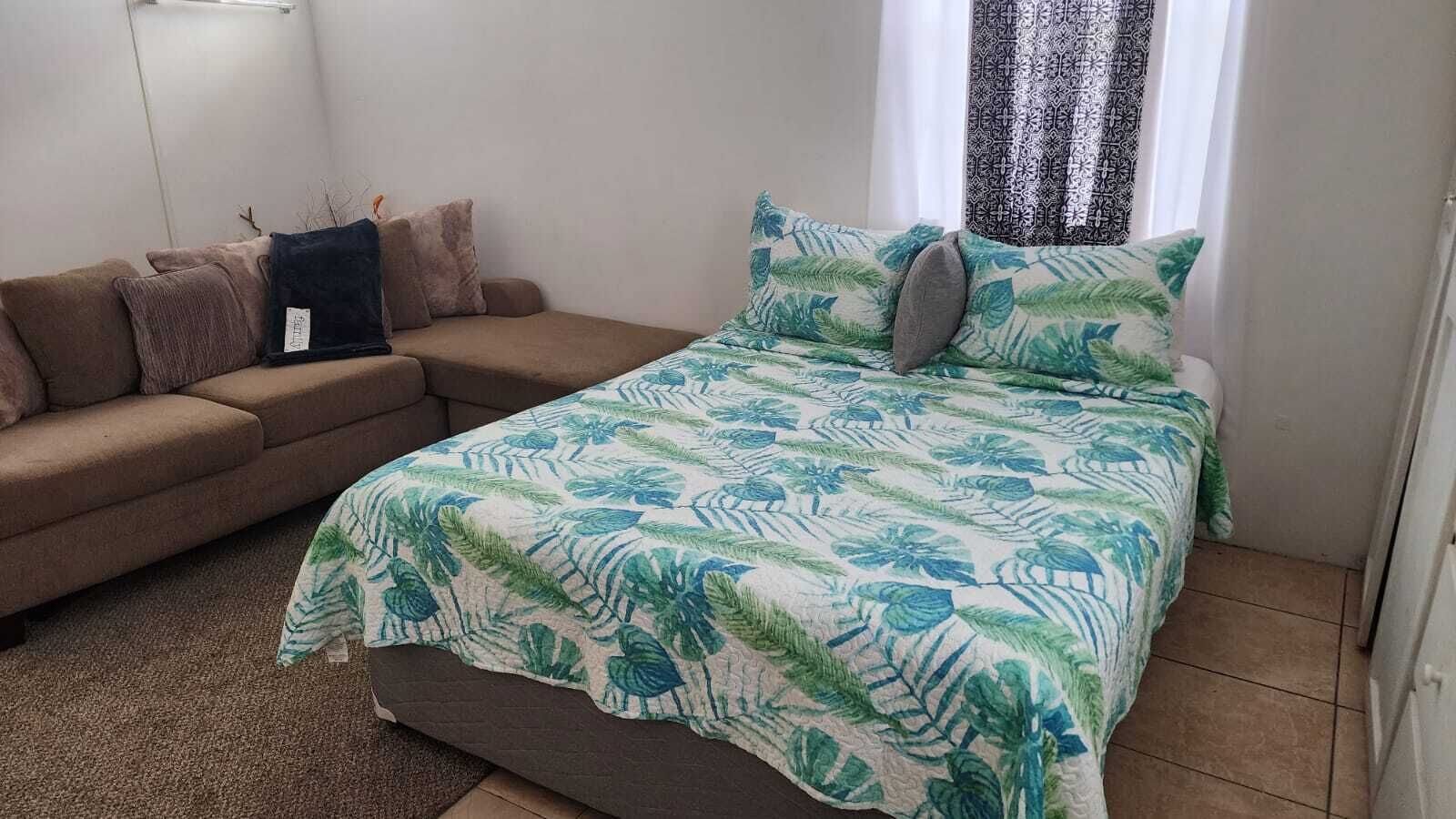 Une chambre à coucher avec un lit, un canapé et une fenêtre ornée de rideaux à motifs.