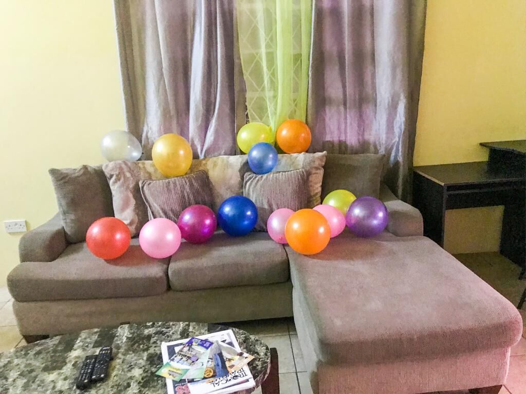 Un salon avec un canapé, une table basse et un téléviseur. Il y a des ballons sur le canapé et une télécommande sur la table basse.