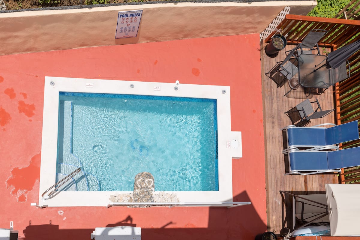 A rectangular pool with a white border, a ladder, and a sign indicating pool rules.