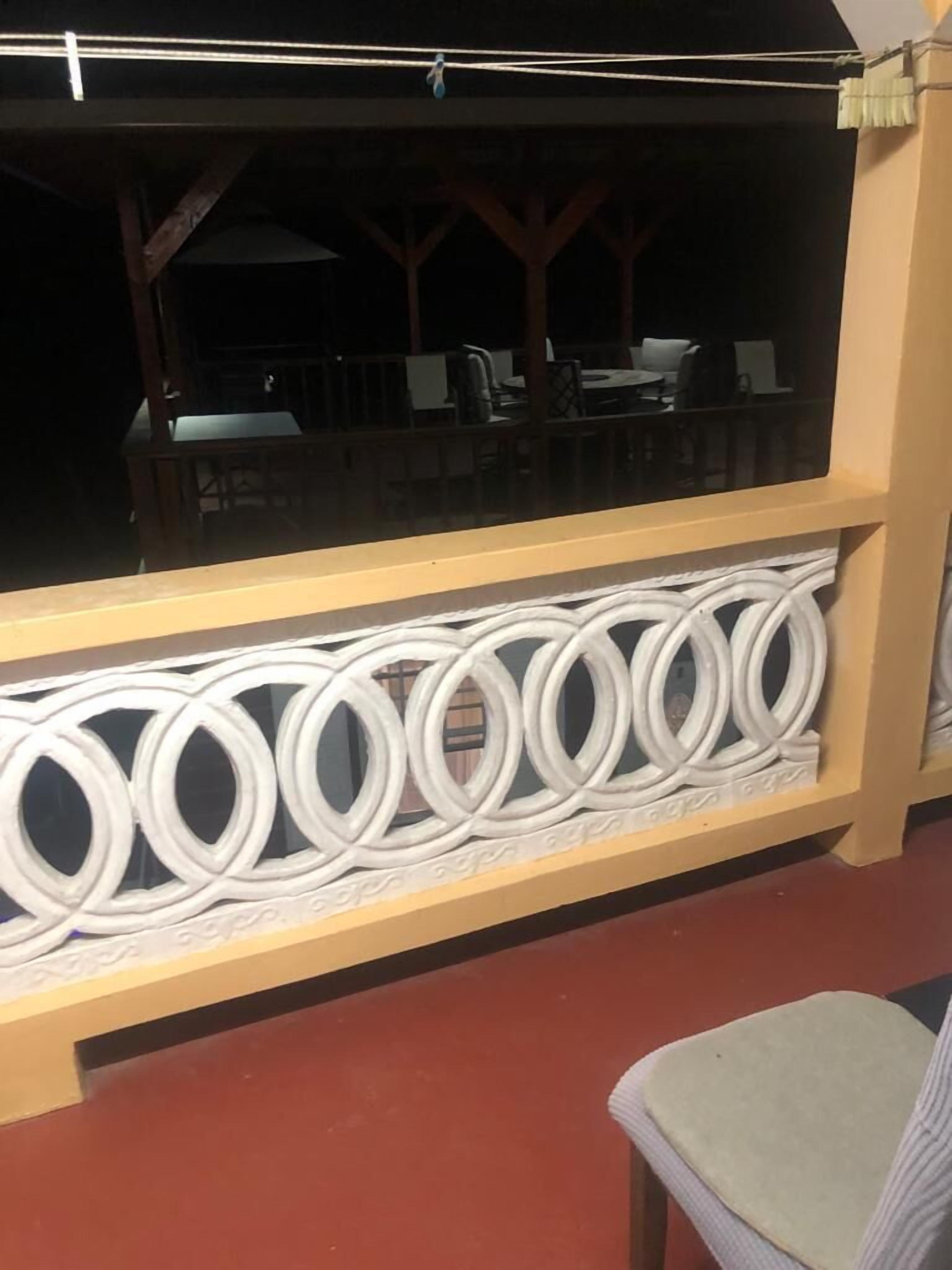 Un balcone con ringhiera decorativa bianca e vista sulla zona salotto all'aperto.
