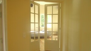 Un pasillo estrecho con una escalera de madera que conduce a una habitación con cama y ventana.