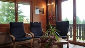 A wooden interior with two blue chairs and a small table with a flower arrangement.