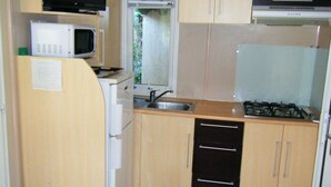 A compact kitchen with a microwave, stove, sink, and a refrigerator.