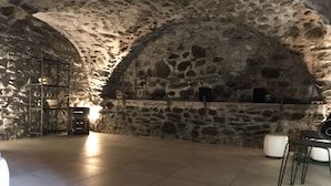 A stone-walled room with a tiled floor, a metal rack with dishes, and a white chair. - ALLEMONT Chalet des Galline DOMAINE VAUJANY ALPE D HUEZ  (Allemond)