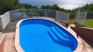 A rectangular swimming pool with a white deck and a metal fence, surrounded by a brick border. - Bungalows with swimming pool with breathtaking sea and mountain views for 4 people each (BOUILLANTE)