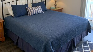 A bedroom with a bed, a ceiling fan, a nightstand, a lamp, a framed picture, and an anchor decoration. - Ocean View Beach House On Jersey Ct just steps to the beach (San Diego)