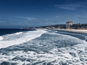 Una playa con olas, un edificio y cielo despejado.