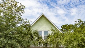 A light green house with a gabled roof, stone pillars, and a front porch with chairs. - Spacious Home. Short Walk to Beach, Beach Shuttle & Shunk Gulley. Pet Friendly! (Santa Rosa Beach)