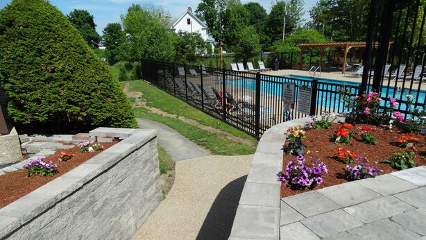 Un espace aménagé avec une piscine, des marches en pierre et des parterres de fleurs.