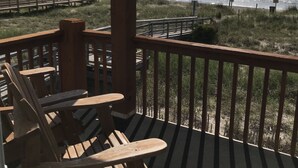 Een houten terras met stoelen en uitzicht op het strand.