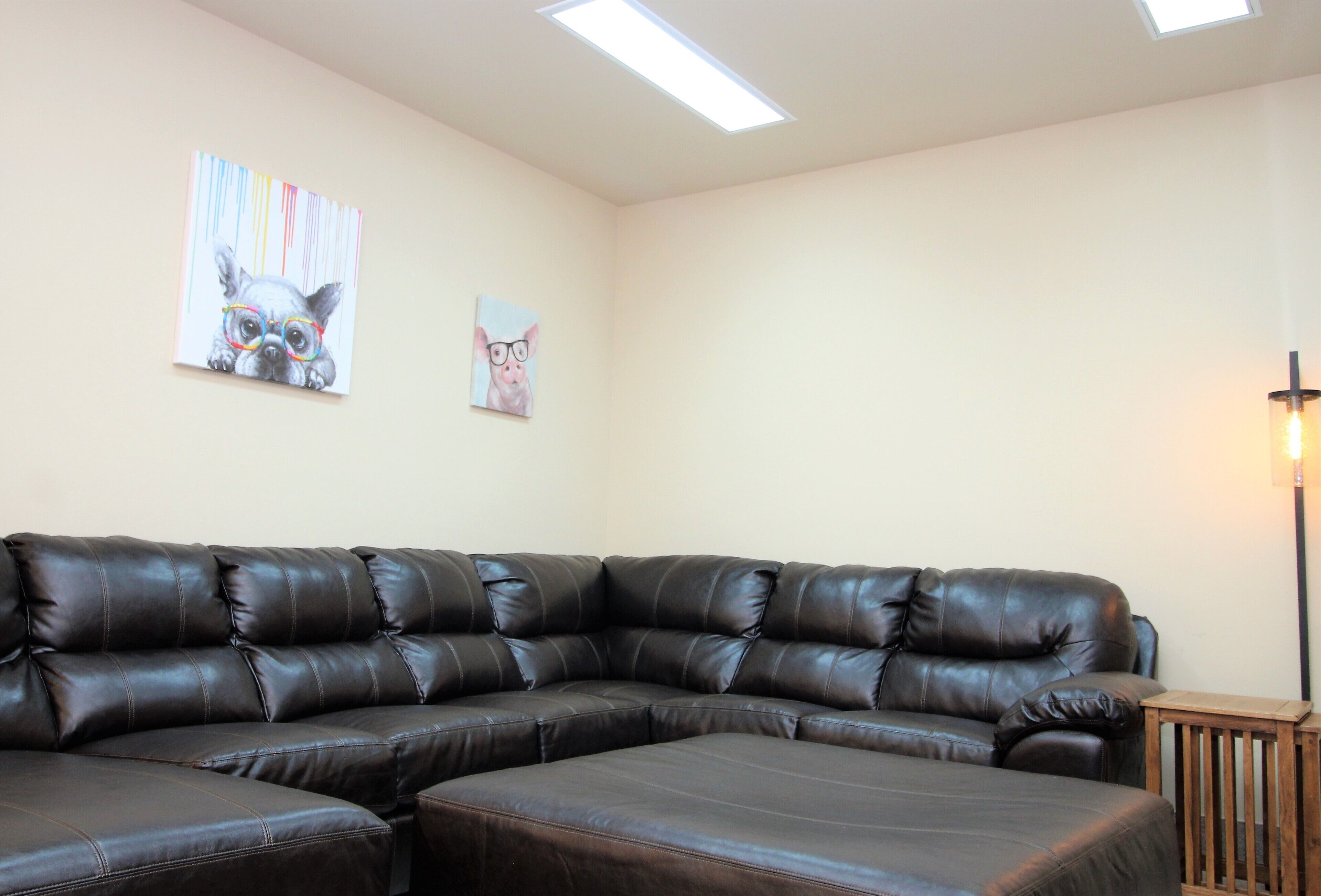 A sectional sofa in a room with two wall-mounted artworks and a floor lamp.