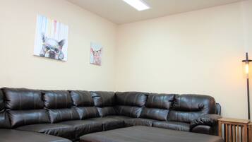 A sectional sofa in a room with two wall-mounted artworks and a floor lamp.