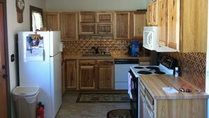 A kitchen with wooden cabinets, a refrigerator, a microwave, and a stove. - 10% Discount to Veterans, First Responders, and Seniors. Note status in request. (Estes Park)