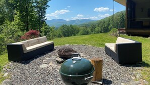 Un patio con mobiliario exterior, una parrilla y vistas a las montañas.