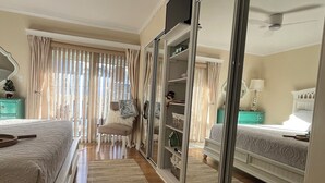 Un dormitorio con dos camas, un espejo grande, un armario y una puerta corrediza.