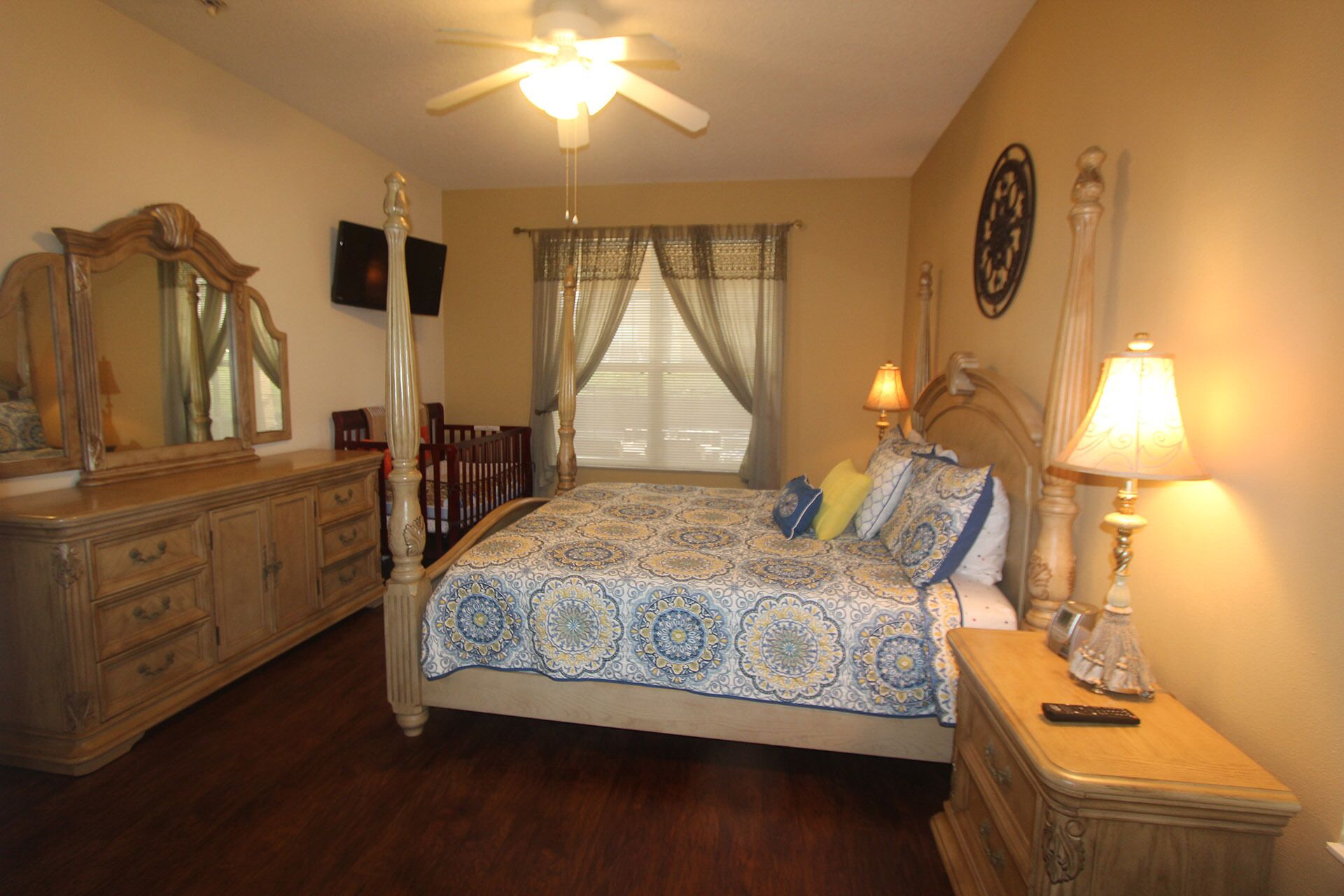 A bedroom with a bed, dresser, nightstand, and ceiling fan.