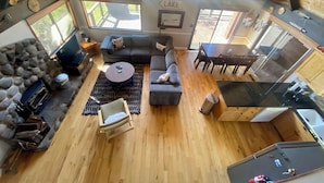 A spacious living area with a stone fireplace, a large sofa, a coffee table, and a dining table. - Fun and Relaxing in Tahoe City! (Tahoe City)
